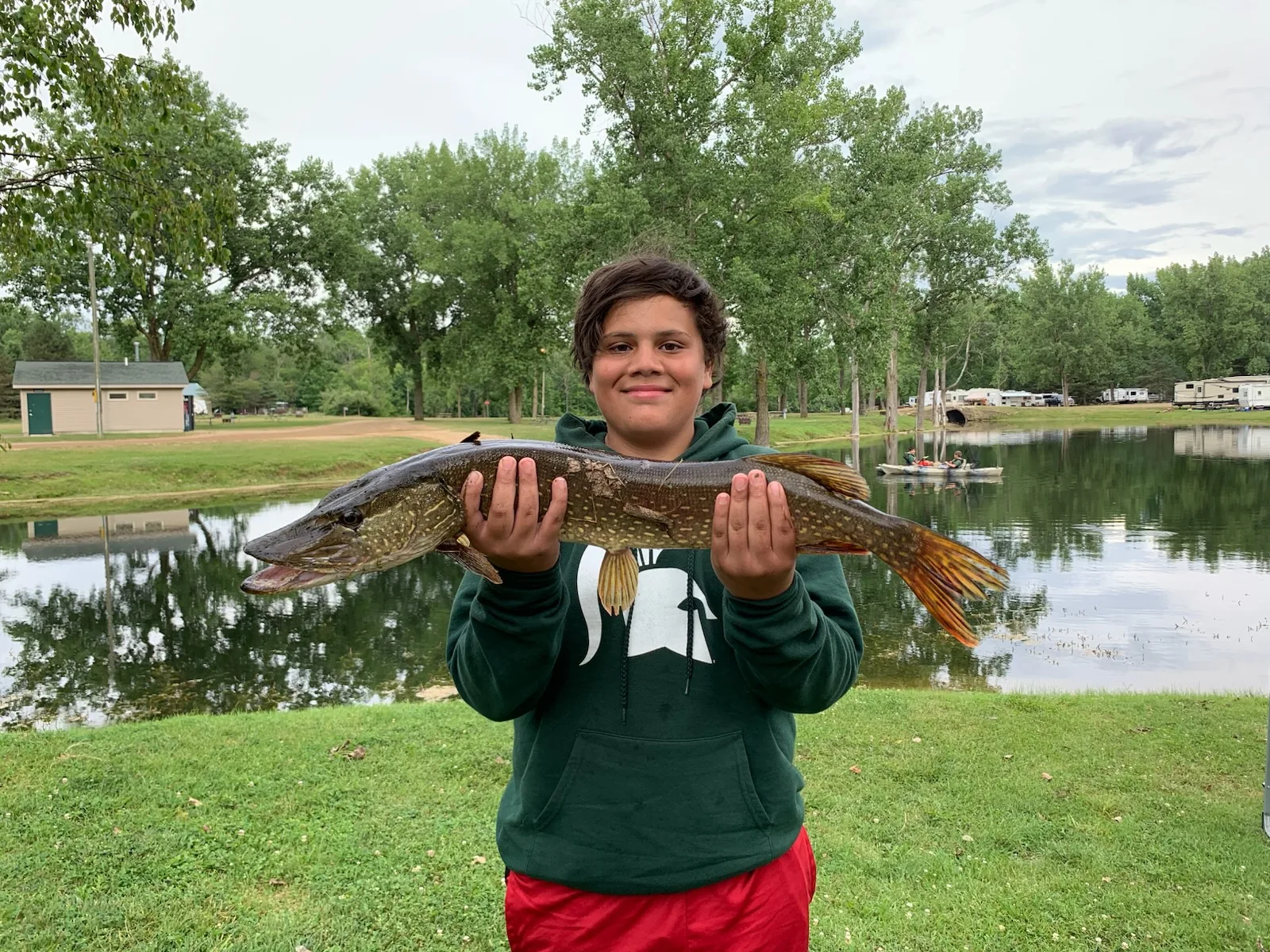 A young angler with a northern pike caught in the lake